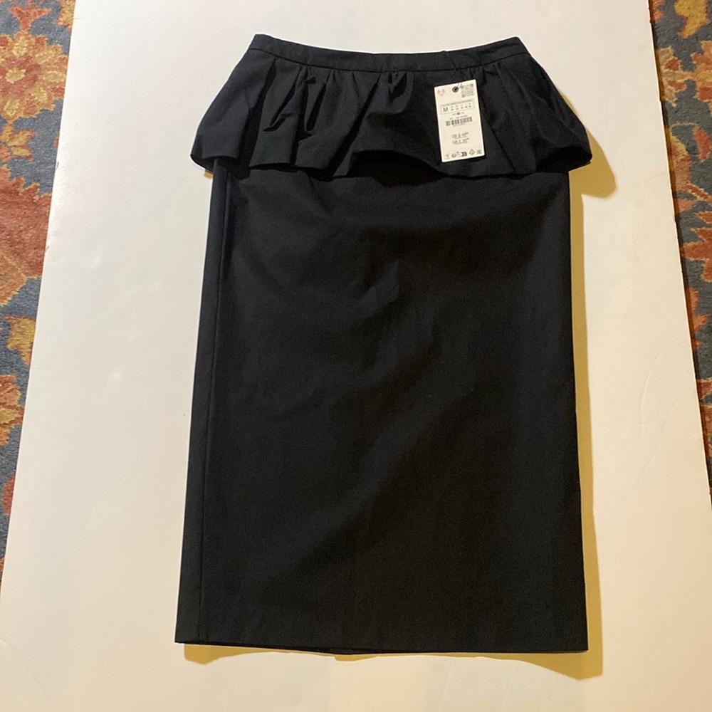 Midi skirt with a mid waist with peplum fabric detail. Hidden inseam zip closure